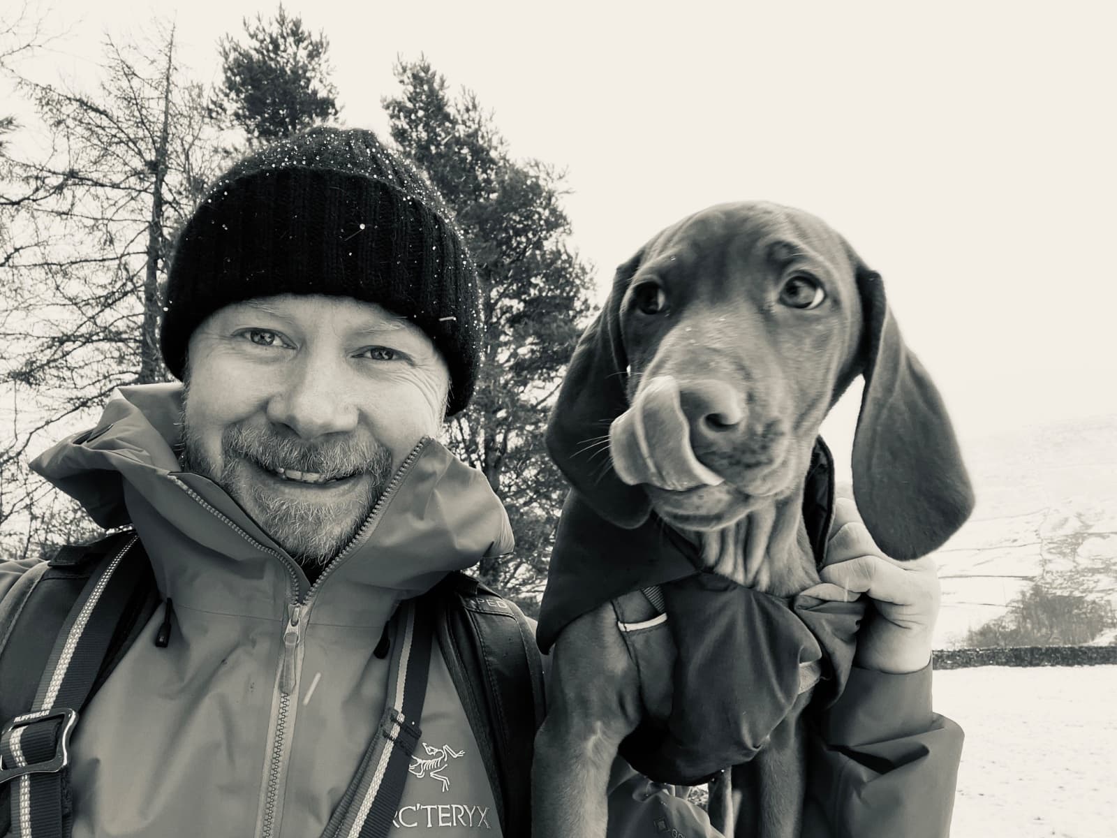 Daniel smiling outdoors in the snow with his Vizsla dog